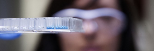 Blurred image of scientist looking closely at pipette