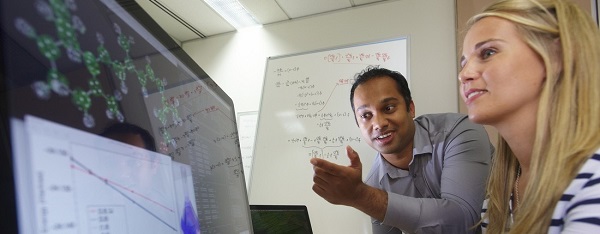 Two people looking at computer screen - one pointing to help explain graph