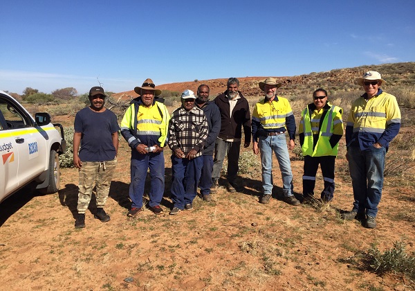 People standing in the outback next to a car.