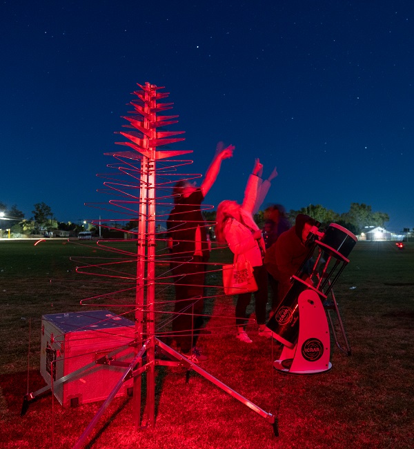 Members of ICRAR’s Outreach team showing the night sky next to a prototype SKA antenna. Credit: ICRAR