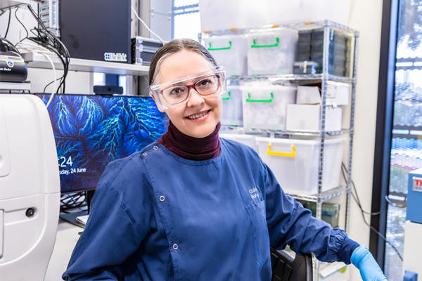 Claudia Vickers, a woman in a blue lab coat, smiling at camera.