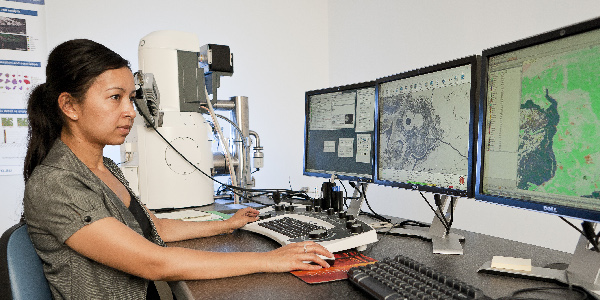Female operator in front of computer screens showing images from QEMSCAN