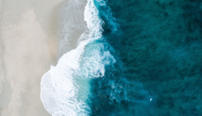 arial view of water lapping onto shore of white sand