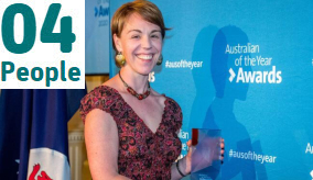 Jess Melbourne-Thomas holding an award in front of a blue background