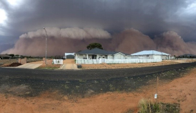 dust clouds rising up behind houses