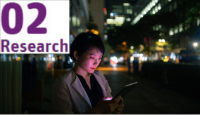 A woman on the street at night looking at a tablet