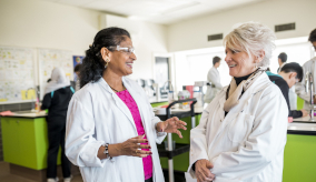 Two female scientists in lab coats talking