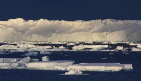 ice shelf and smaller ice bergs and a dark blue sky