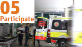 Blurry image of an ambulance in front of a hospital with staff wheeling out a patient