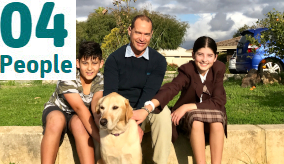 dad with two children and a dog sitting on a fence