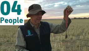 A scientist in a field with a mouse