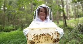 Image of woman holding beehive. 