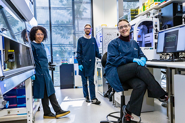 Three scientists smiling at the camera, in a lab.